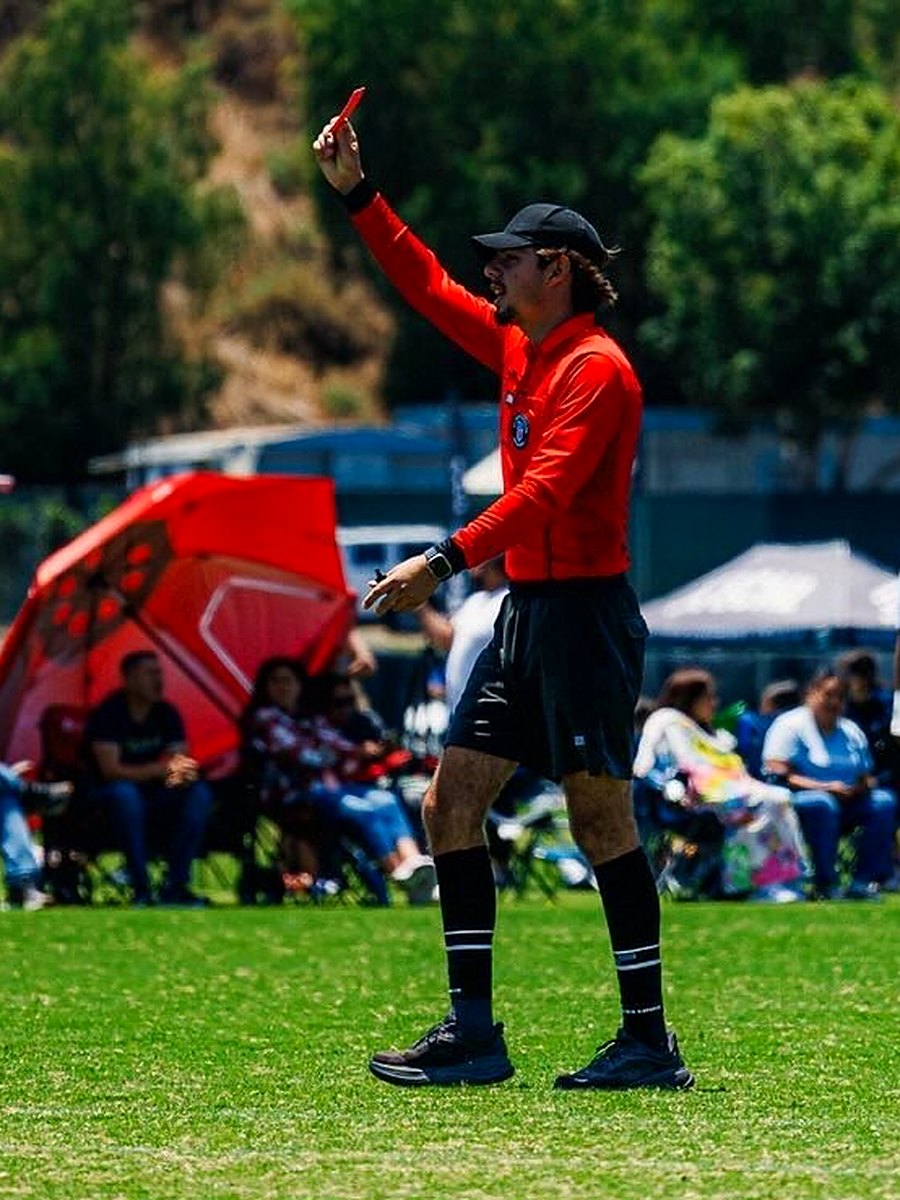 Santiago refereeing a match, showing a red card